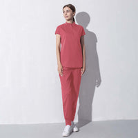 Woman in fashionable red salon workwear standing against white background, featuring stylish and professional design ideal for beauty aesthetics.